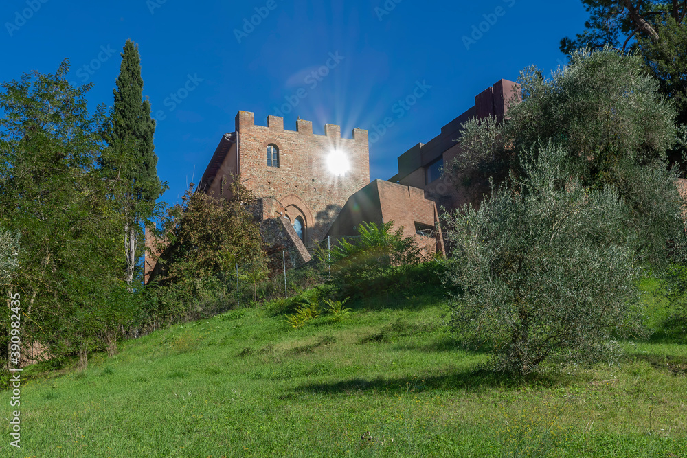 The sun reflects in one of the windows of the walls of Certaldo Alto, Florence, Italy, on a sunny day