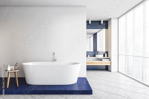 Blue and white bathroom with bathtub and sinks on marble floor