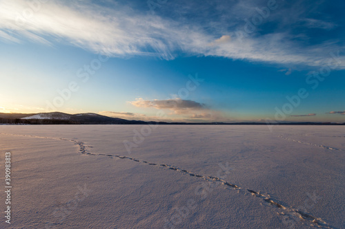 frozen lake in winter on a background of blue sky with clouds