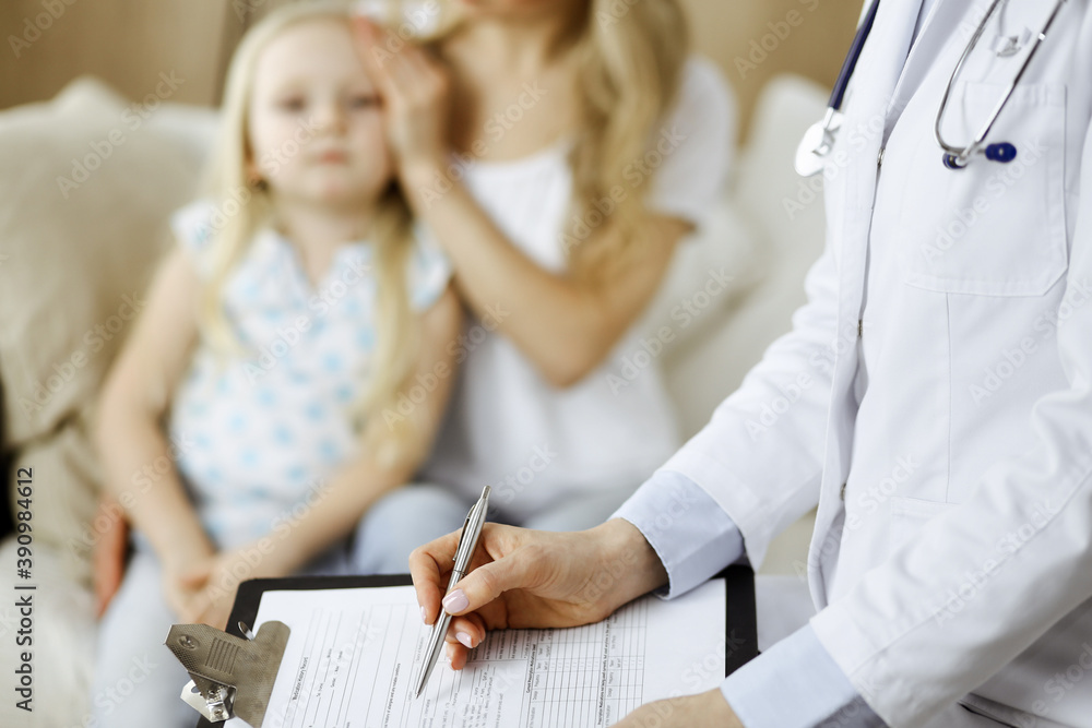 Obraz premium Doctor and patient. Pediatrician using clipboard while examining little girl with her mother at home. Sick and unhappy child at medical exam. Medicine concept