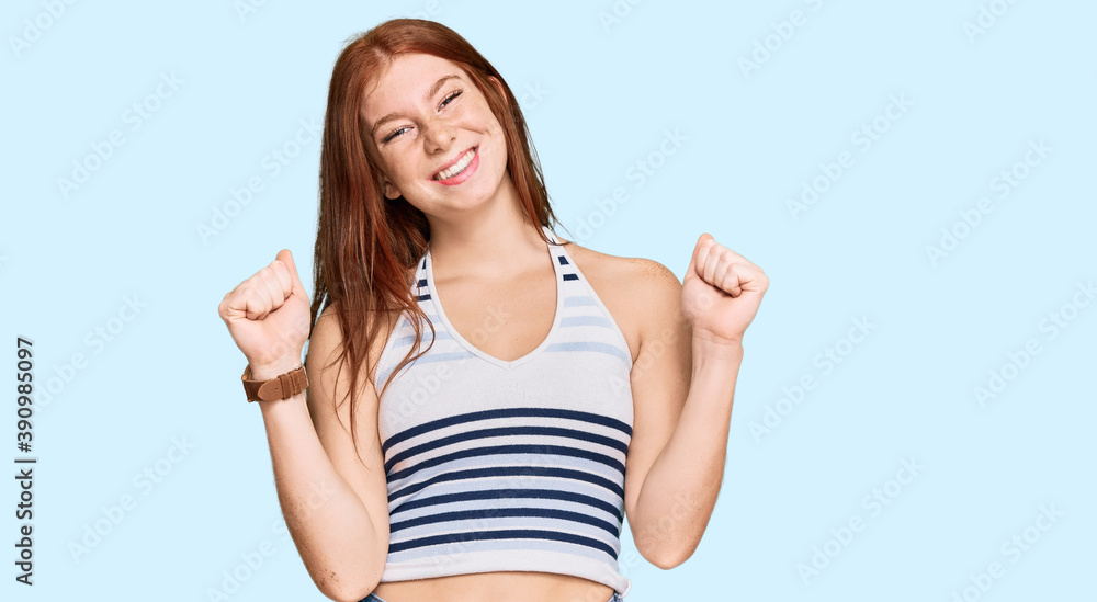 Fototapeta premium Young read head woman wearing casual clothes celebrating surprised and amazed for success with arms raised and open eyes. winner concept.