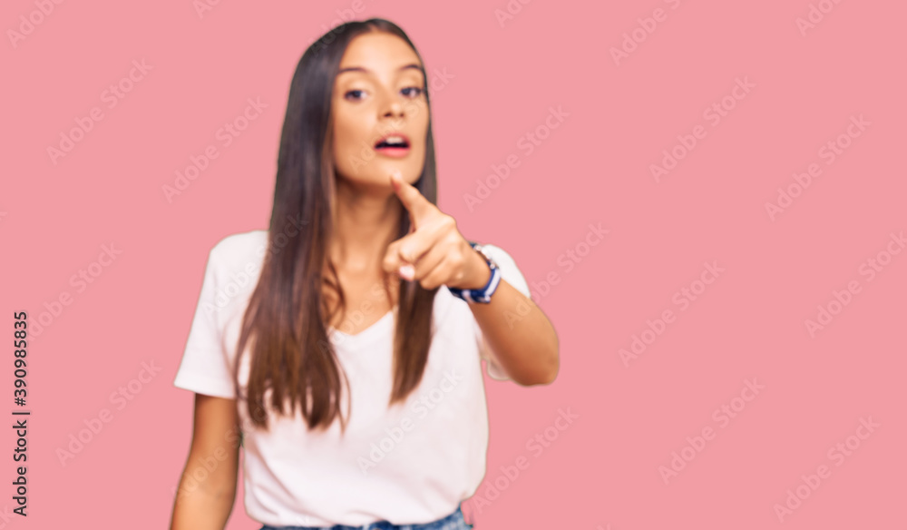Young hispanic woman wearing casual white tshirt pointing displeased and frustrated to the camera, angry and furious with you Young hispanic woman wearing casual white tshirt pointing displeased and frustrated to the camera, angry and furious with you