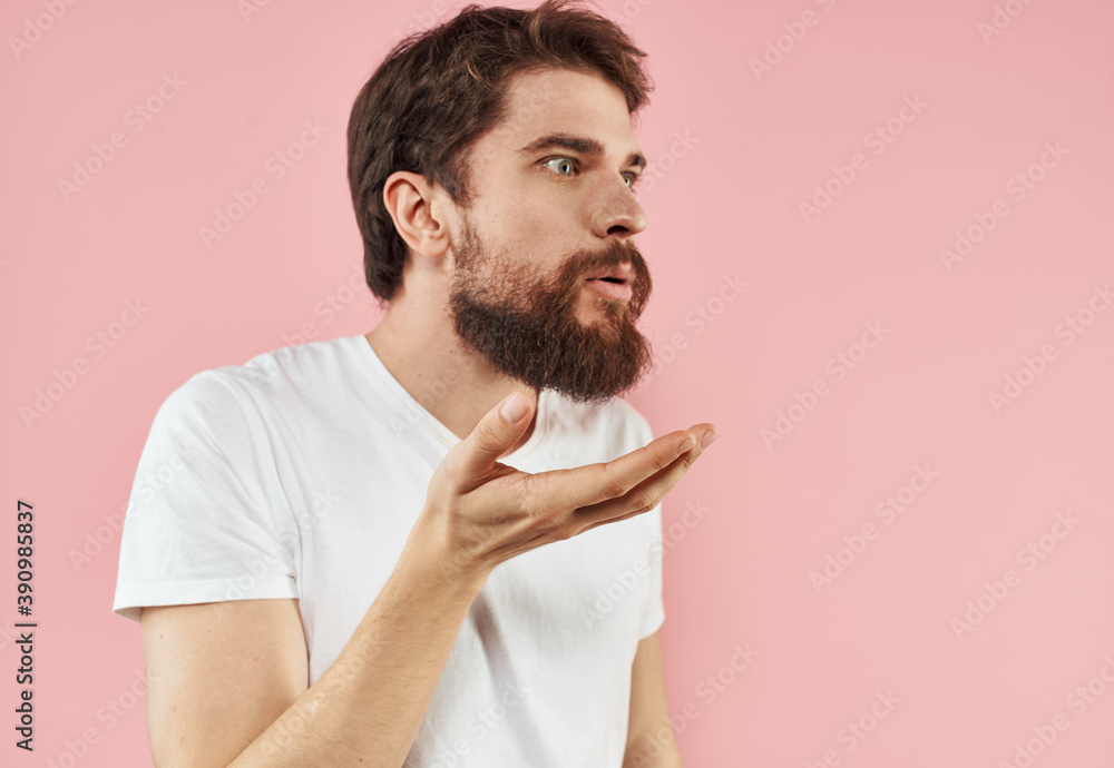 A man with a beard gestures with his hands on a pink background cropped view of a white t-shirt A man with a beard gestures with his hands on a pink background cropped view of a white t-shirt