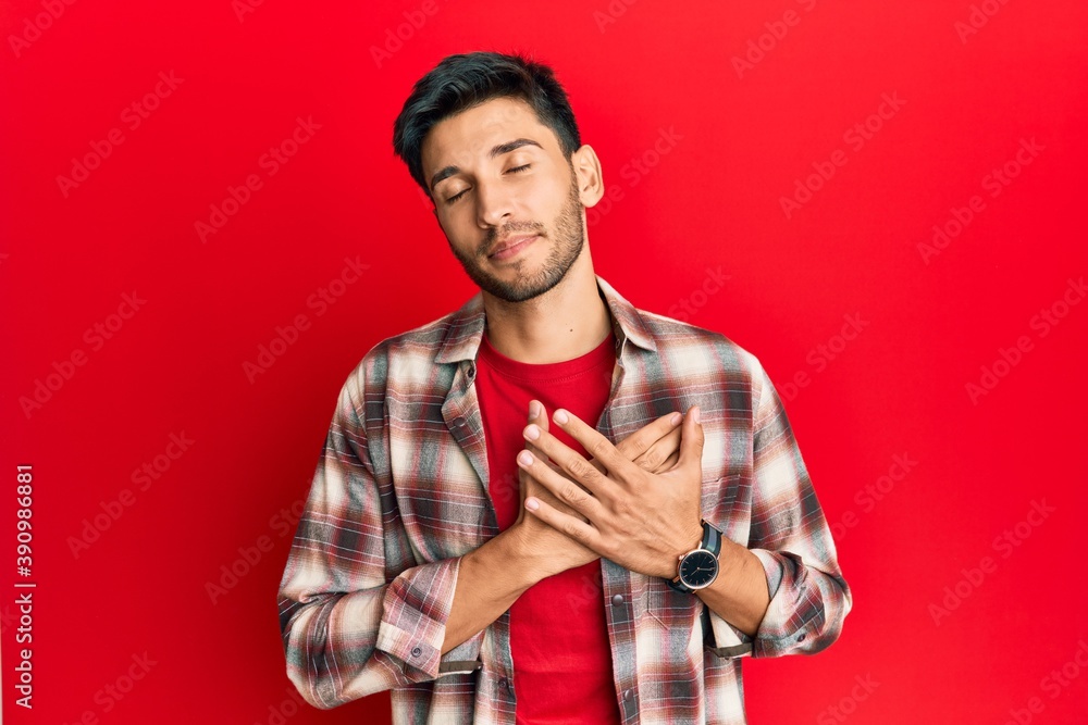 Young handsome man wearing casual clothes smiling with hands on chest, eyes closed with grateful gesture on face. health concept. Young handsome man wearing casual clothes smiling with hands on chest, eyes closed with grateful gesture on face. health concept.