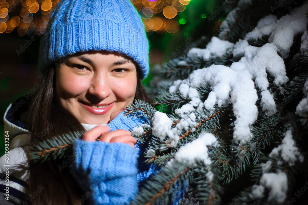 Close up Winter portrait of a young smiling woman in a blue hat at night. Close up Winter portrait of a young smiling woman in a blue hat at night.