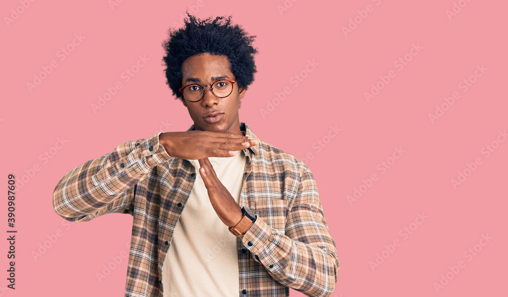 Handsome african american man with afro hair wearing casual clothes and glasses doing time out gesture with hands, frustrated and serious face Handsome african american man with afro hair wearing casual clothes and glasses doing time out gesture with hands, frustrated and serious face