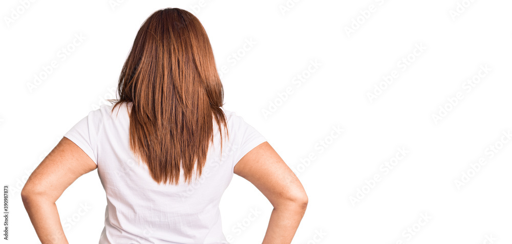 Middle age latin woman wearing casual white tshirt standing backwards looking away with arms on body Middle age latin woman wearing casual white tshirt standing backwards looking away with arms on body