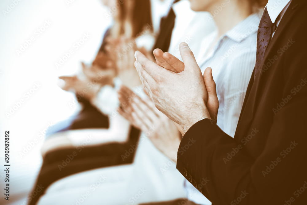 Obraz premium Business people clapping and applause at meeting or conference, close-up of hands. Group of unknown businessmen and women in modern white office. Success teamwork or corporate coaching concept
