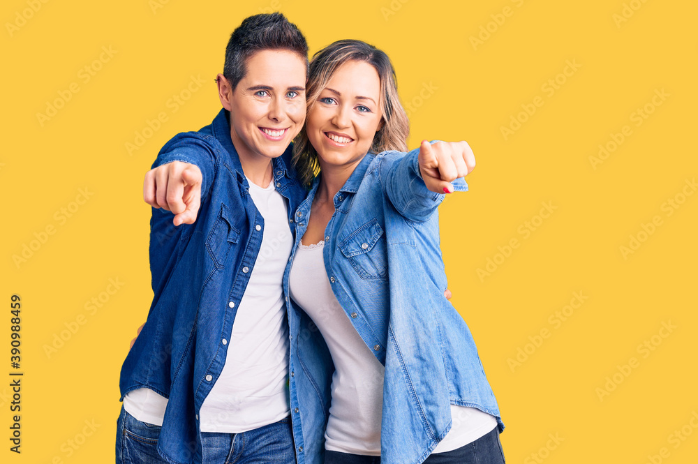 Couple of women wearing casual clothes pointing to you and the camera with fingers, smiling positive and cheerful Couple of women wearing casual clothes pointing to you and the camera with fingers, smiling positive and cheerful
