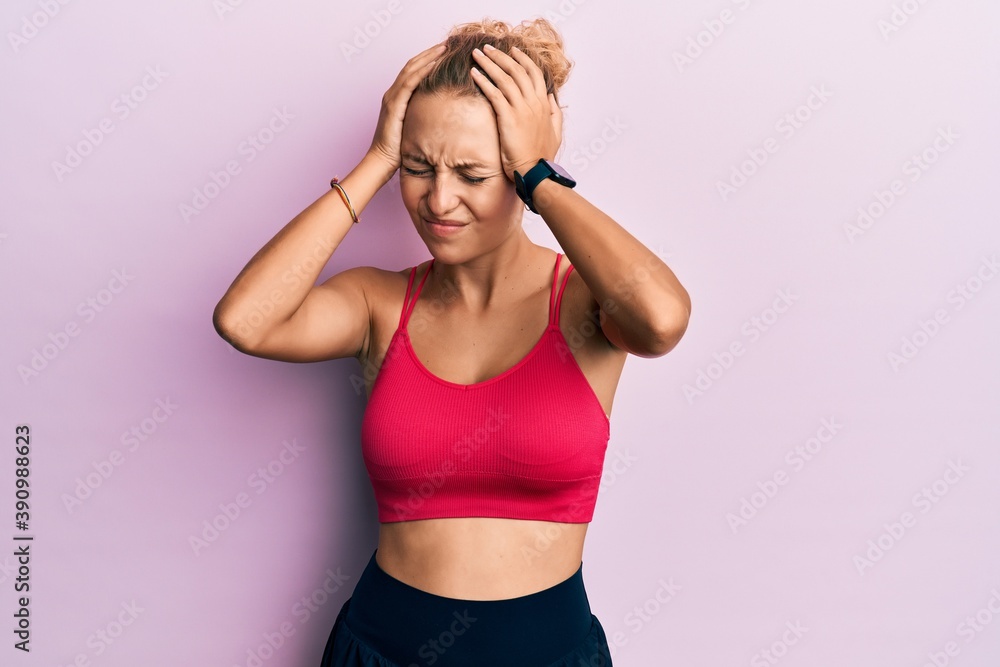 Beautiful caucasian woman wearing sportswear suffering from headache desperate and stressed because pain and migraine. hands on head. Beautiful caucasian woman wearing sportswear suffering from headache desperate and stressed because pain and migraine. hands on head.
