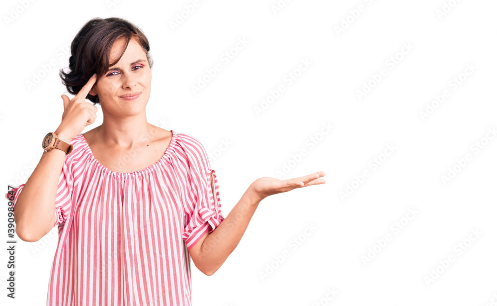 Beautiful young woman with short hair wearing casual summer clothes confused and annoyed with open palm showing copy space and pointing finger to forehead. think about it. Beautiful young woman with short hair wearing casual summer clothes confused and annoyed with open palm showing copy space and pointing finger to forehead. think about it.