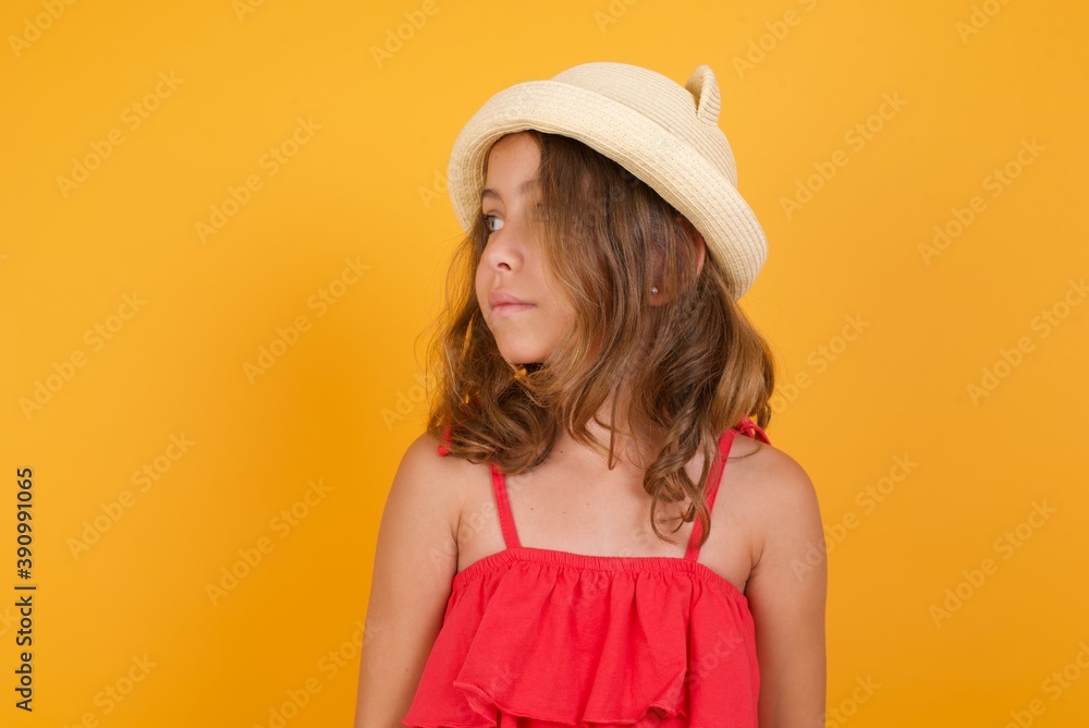 Side view of young happy smiling young Caucasian girl standing against yellow background Side view of young happy smiling young Caucasian girl standing against yellow background