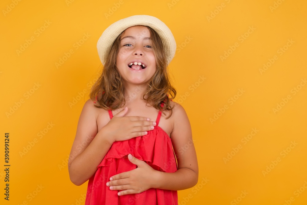 young Caucasian girl standing against yellow background keeps hands crossed, laughs out loud at good joke, wears casual clothes. young Caucasian girl standing against yellow background keeps hands crossed, laughs out loud at good joke, wears casual clothes.