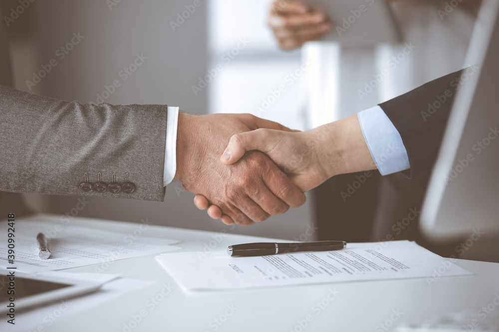 Obraz premium Business people shaking hands finishing contract signing, close-up. Business communication concept. Handshake and marketing