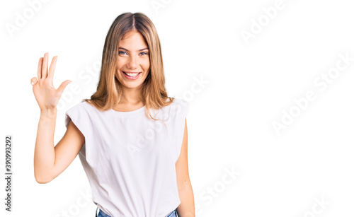 Wallpaper Mural Beautiful caucasian woman with blonde hair wearing casual white tshirt showing and pointing up with fingers number four while smiling confident and happy. Torontodigital.ca