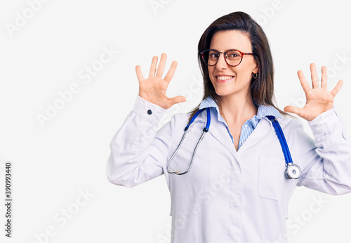 Young beautiful woman wearing doctor stethoscope and glasses showing and pointing up with fingers number ten while smiling confident and happy.