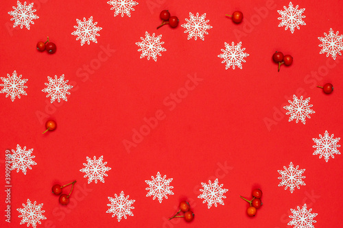 Xmas pattern. White snowflakes  red berry in Christmas composition on red background for greeting card. Flat lay  top view  copy space.