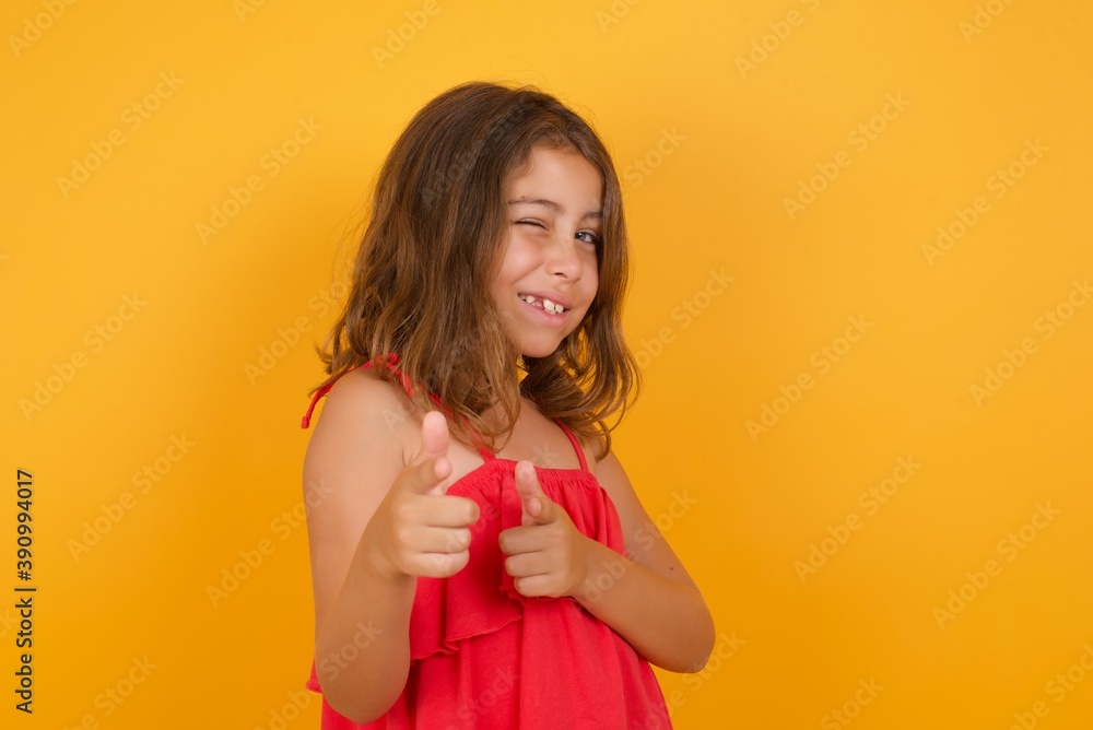 Hey you, bang. Joyful and charismatic good-looking young Caucasian girl standing against yellow background winking and pointing with finger pistols at camera happily and cheeky. Hey you, bang. Joyful and charismatic good-looking young Caucasian girl standing against yellow background winking and pointing with finger pistols at camera happily and cheeky.