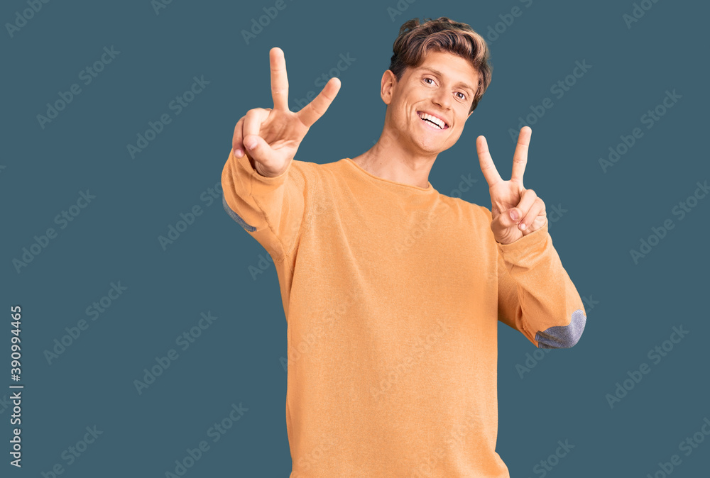 Young handsome man wearing casual clothes smiling looking to the camera showing fingers doing victory sign. number two. Young handsome man wearing casual clothes smiling looking to the camera showing fingers doing victory sign. number two.