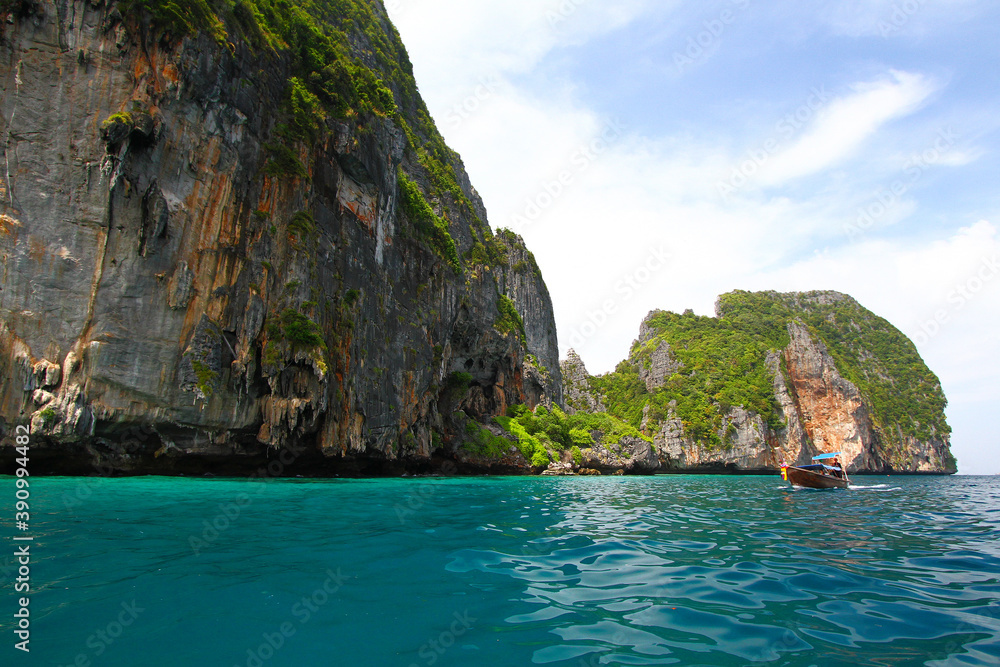 Big stone or rock mountain or island and long tail boat on sea with blue sky and white cloud background at Krabi, Thailand. Beauty in nature and Landmark for tourist travel in south of Thailand. Big stone or rock mountain or island and long tail boat on sea with blue sky and white cloud background at Krabi, Thailand. Beauty in nature and Landmark for tourist travel in south of Thailand.