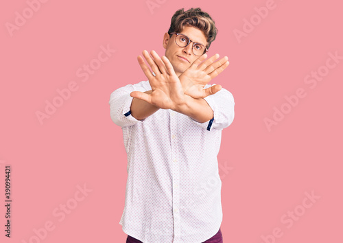 Young handsome man wearing business clothes and glasses rejection expression crossing arms and palms doing negative sign, angry face © Krakenimages.com