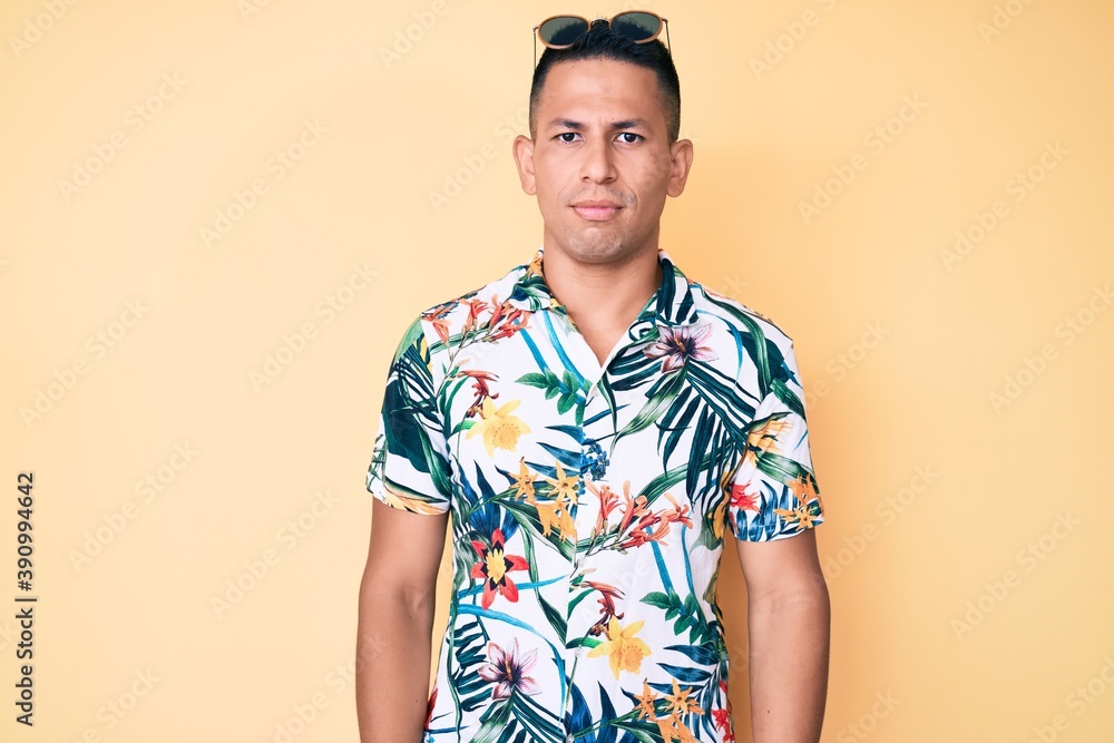 Young handsome latin man wearing summer clothes relaxed with serious expression on face. simple and natural looking at the camera. Young handsome latin man wearing summer clothes relaxed with serious expression on face. simple and natural looking at the camera.