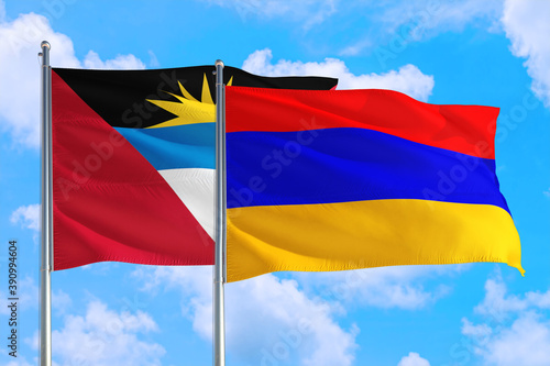 Armenia and Antigua and Barbuda national flag waving in the windy deep blue sky. Diplomacy and international relations concept.