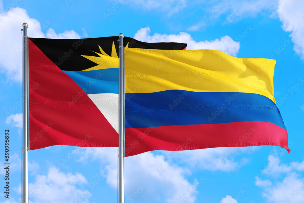 Colombia and Antigua and Barbuda national flag waving in the windy deep blue sky. Diplomacy and international relations concept. Colombia and Antigua and Barbuda national flag waving in the windy deep blue sky. Diplomacy and international relations concept.