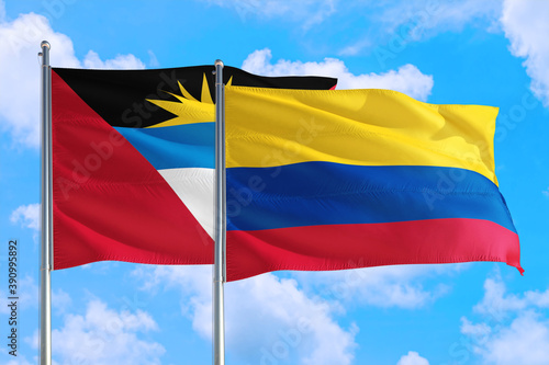 Colombia and Antigua and Barbuda national flag waving in the windy deep blue sky. Diplomacy and international relations concept.