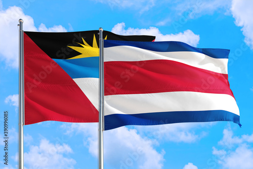 Costa Rica and Antigua and Barbuda national flag waving in the windy deep blue sky. Diplomacy and international relations concept.