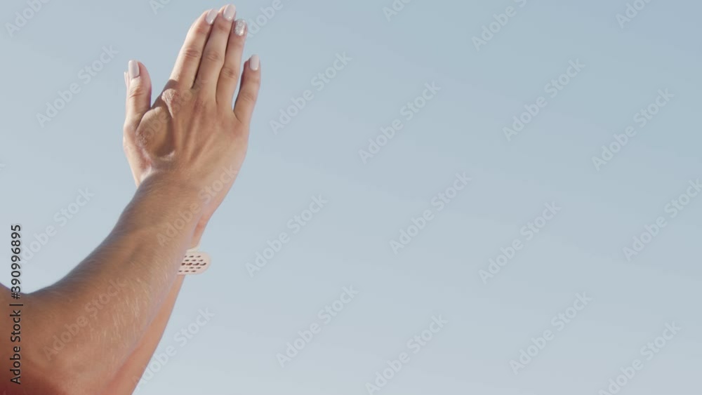 Hands of a woman athlete close up clapping her hands on a background of blue sky. Cotton female hands before the start in athletics