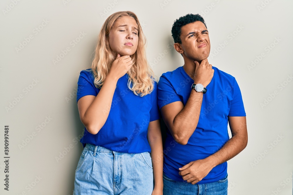 Young interracial couple wearing casual clothes touching painful neck, sore throat for flu, clod and infection Young interracial couple wearing casual clothes touching painful neck, sore throat for flu, clod and infection