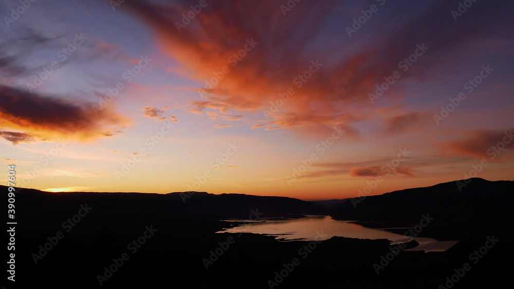 Stunning panorama view over reservoir Bin el Ouidane Dam with water reflection and beautiful colored dramatic sky with orange clouds near Beni Mellal, Morocco. 