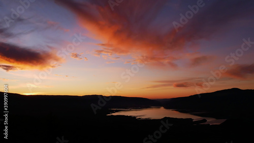 Stunning panorama view over reservoir Bin el Ouidane Dam with water reflection and beautiful colored dramatic sky with orange clouds near Beni Mellal, Morocco. 
