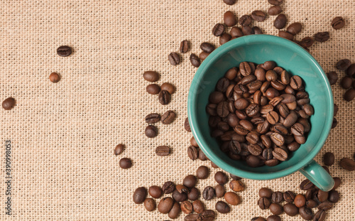 green coffee cup with grains and raffia cloth background 