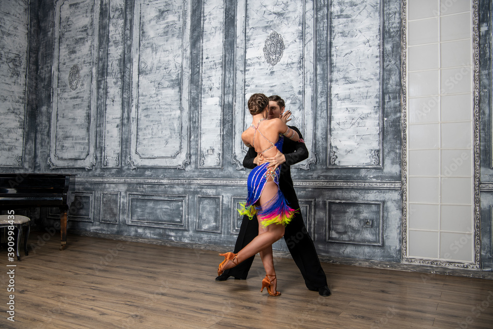 Fototapeta premium beautiful couple with dance costumes dancing latin dances in the hall