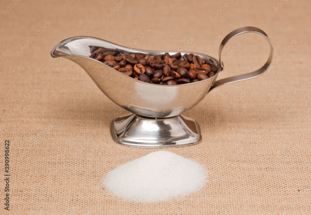 Fototapeta premium pile of sugar and silver container with coffee, on raffia cloth