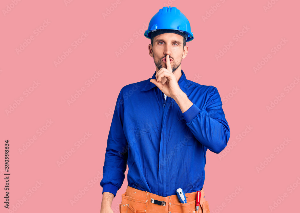 Young handsome man wearing worker uniform and hardhat asking to be quiet with finger on lips. silence and secret concept. Young handsome man wearing worker uniform and hardhat asking to be quiet with finger on lips. silence and secret concept.