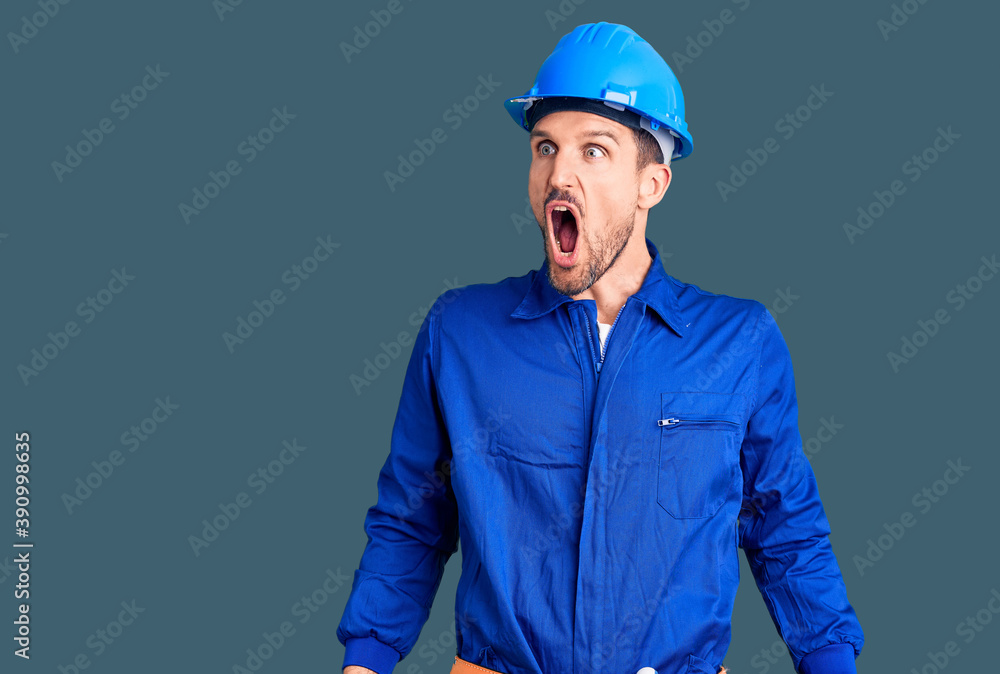 Young handsome man wearing worker uniform and hardhat doing stop gesture with hands palms, angry and frustration expression Young handsome man wearing worker uniform and hardhat doing stop gesture with hands palms, angry and frustration expression