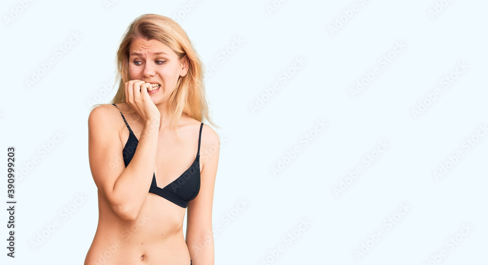Obraz premium Young beautiful blonde woman wearing bikini looking stressed and nervous with hands on mouth biting nails. anxiety problem.