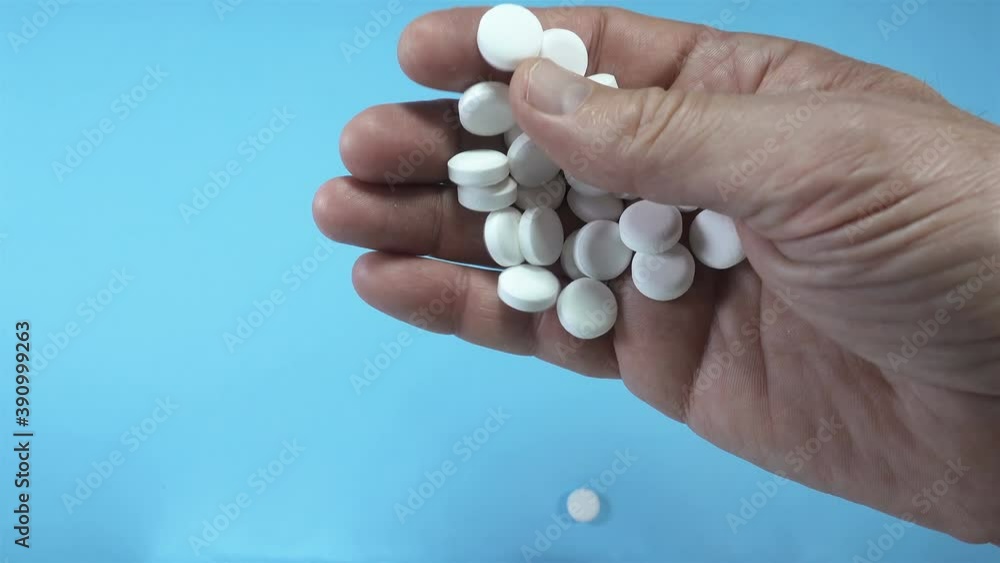 4K view of white pills on a male palm falling on a blue surface. 4K view of white pills on a male palm falling on a blue surface.