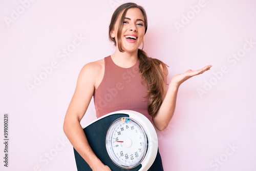 Foto Beautiful young caucasian woman holding weight machine to balance weight loss ce