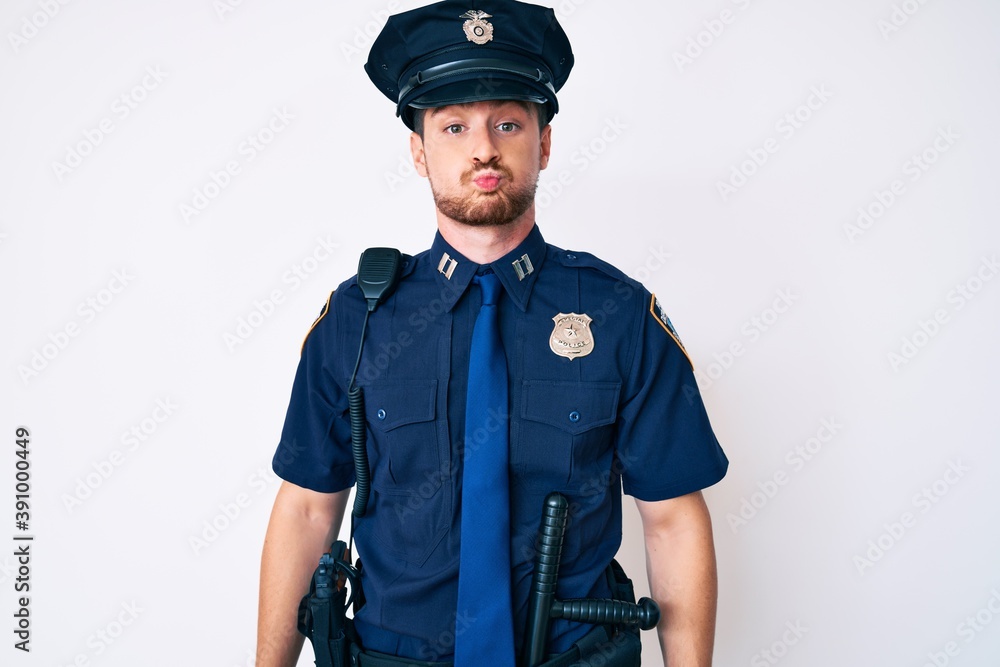 Young caucasian man wearing police uniform puffing cheeks with funny face. mouth inflated with air, crazy expression. Young caucasian man wearing police uniform puffing cheeks with funny face. mouth inflated with air, crazy expression.