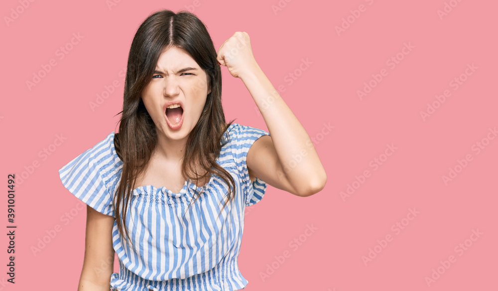 Young beautiful caucasian girl wearing casual clothes angry and mad raising fist frustrated and furious while shouting with anger. rage and aggressive concept. Young beautiful caucasian girl wearing casual clothes angry and mad raising fist frustrated and furious while shouting with anger. rage and aggressive concept.