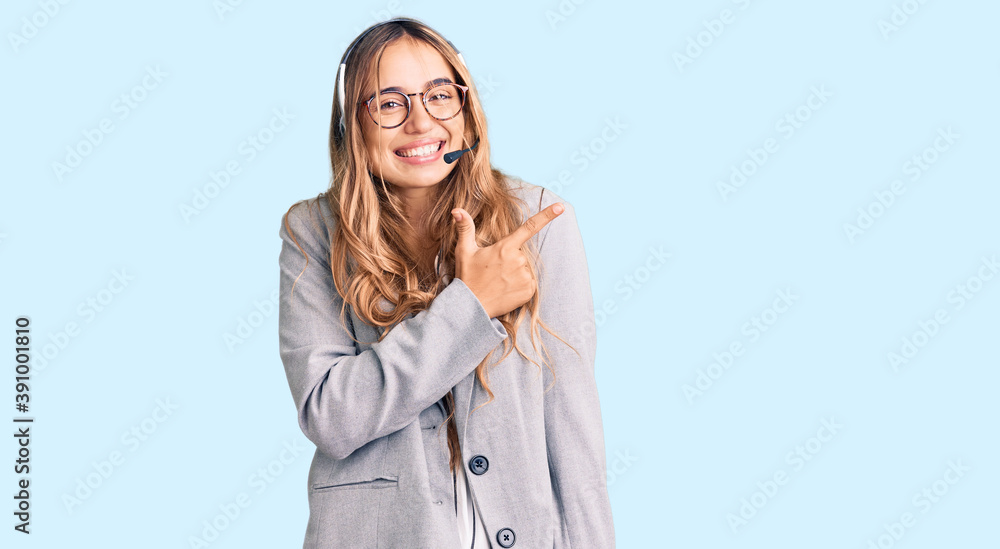 Young beautiful blonde woman wearing call center agent headset cheerful with a smile of face pointing with hand and finger up to the side with happy and natural expression on face Young beautiful blonde woman wearing call center agent headset cheerful with a smile of face pointing with hand and finger up to the side with happy and natural expression on face