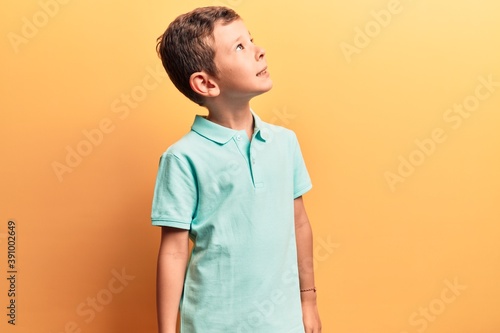 Cute blond kid wearing casual clothes looking to side, relax profile pose with natural face and confident smile.