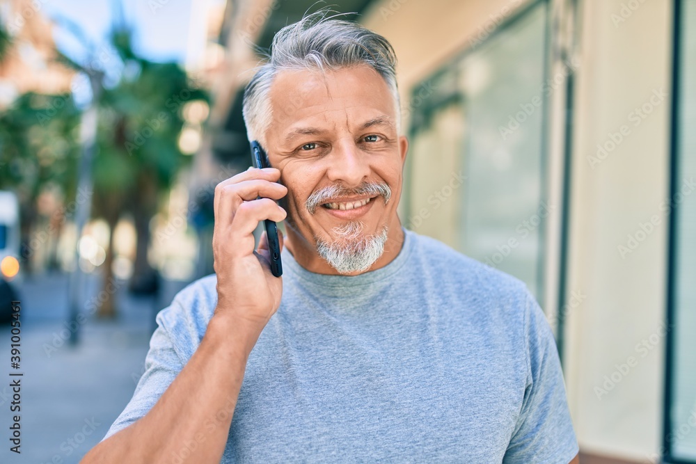 Middle age hispanic grey-haired man smiling happy talking on the smartphone at the city. Middle age hispanic grey-haired man smiling happy talking on the smartphone at the city.