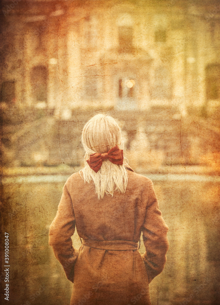 blonde in coat and bow with old castle on background.
