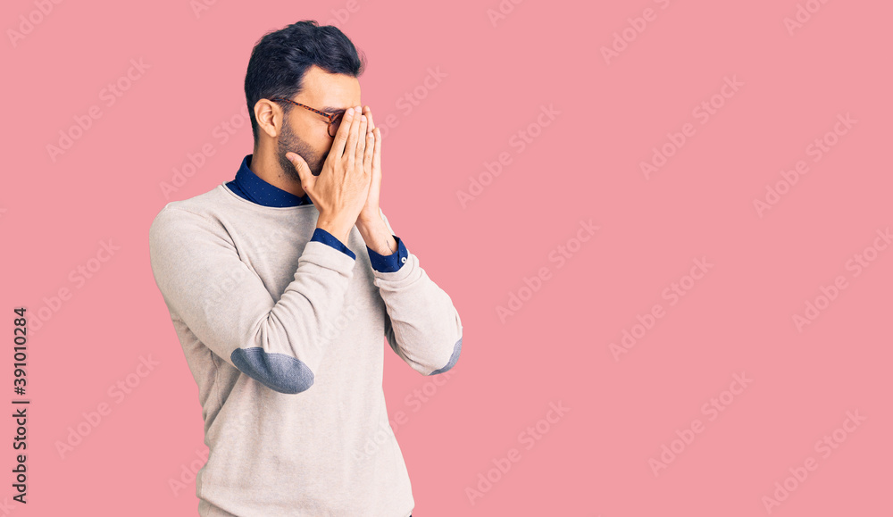 Young handsome hispanic man wearing elegant clothes and glasses with sad expression covering face with hands while crying. depression concept. Young handsome hispanic man wearing elegant clothes and glasses with sad expression covering face with hands while crying. depression concept.