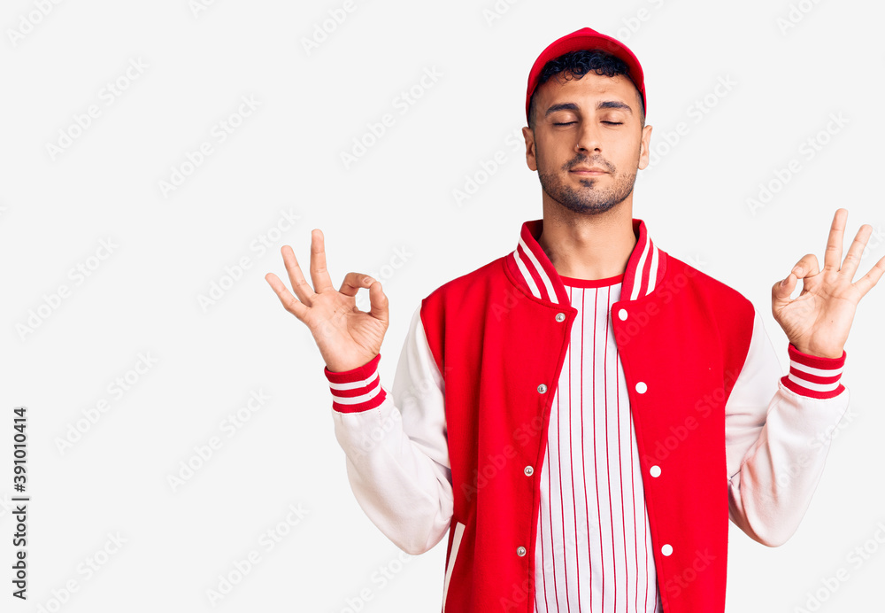 Young hispanic man wearing baseball uniform relax and smiling with eyes closed doing meditation gesture with fingers. yoga concept. Young hispanic man wearing baseball uniform relax and smiling with eyes closed doing meditation gesture with fingers. yoga concept.